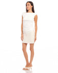 Woman wearing a white Tasha Side-Shirred Top with cap sleeves and boatneck, styled with a beige skirt and heels.