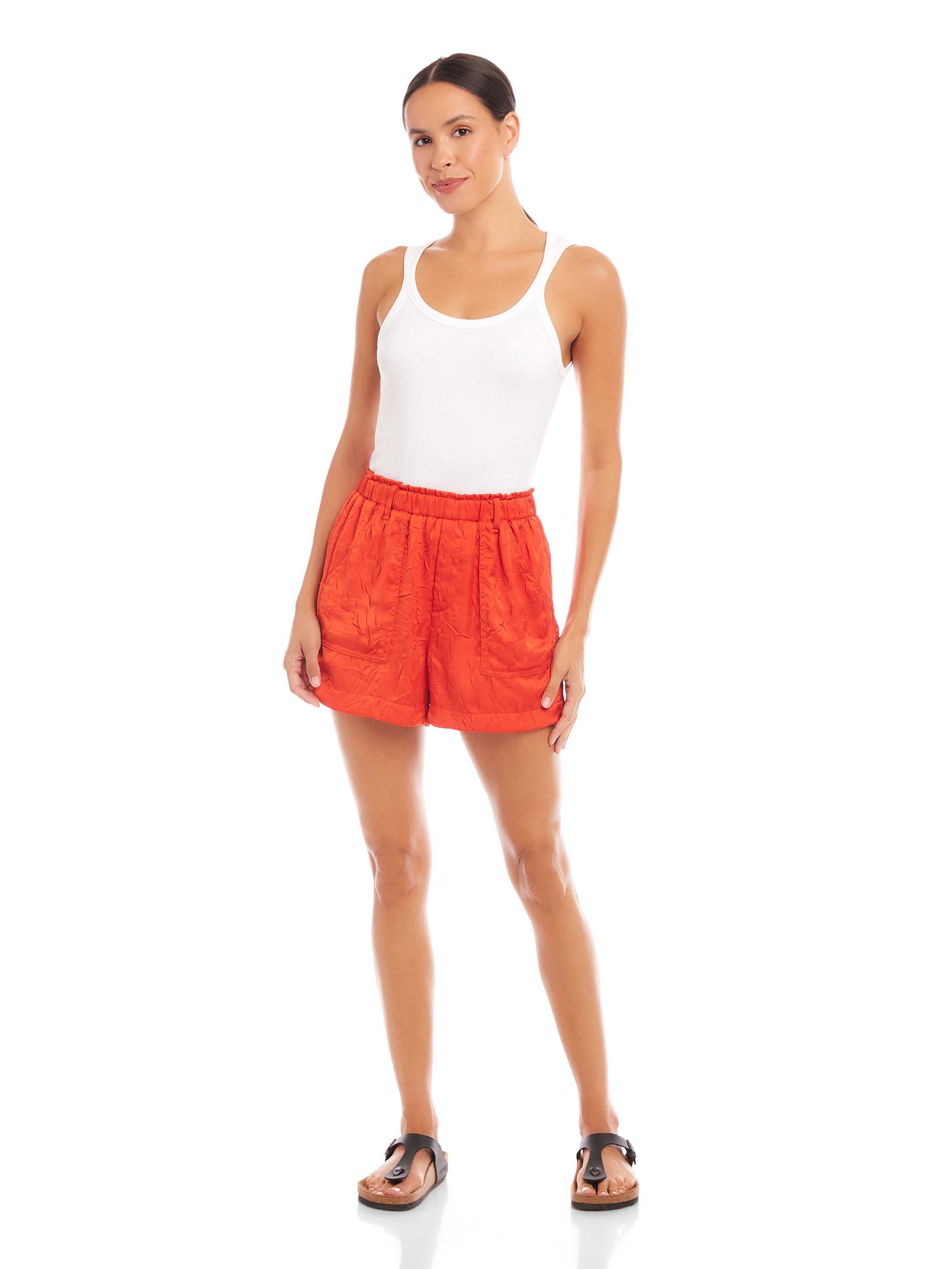 Woman wearing orange Becca Shorts made of textured crushed satin with elasticized waist and front pockets