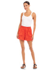 Woman wearing orange Becca Shorts made of textured crushed satin with elasticized waist and front pockets