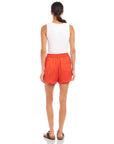 Woman wearing orange high-waist Becca Shorts with elasticized waist and front patch pockets, back view