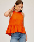 Woman wearing orange Floren Ruffle Hem crushed satin halter top with high-low hem and back tie closure.