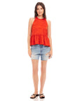 Woman wearing Floren ruffle hem halter top in red with distressed denim shorts and black sandals