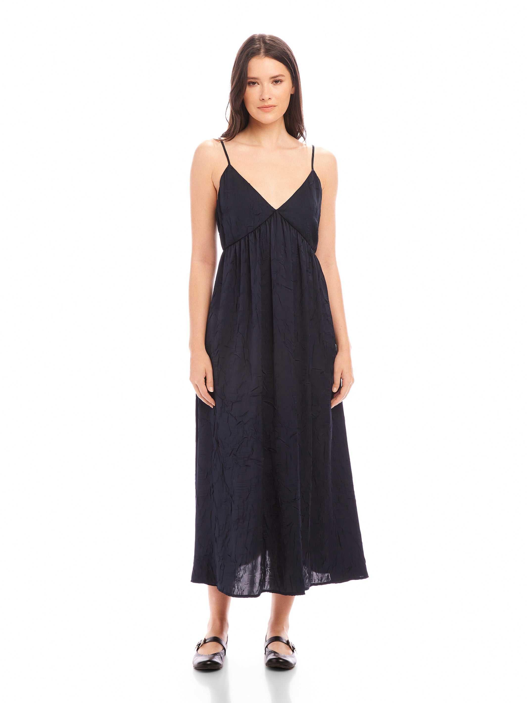 Woman wearing a black Leanna Midi Dress with adjustable spaghetti straps and V-neckline made of crushed satin