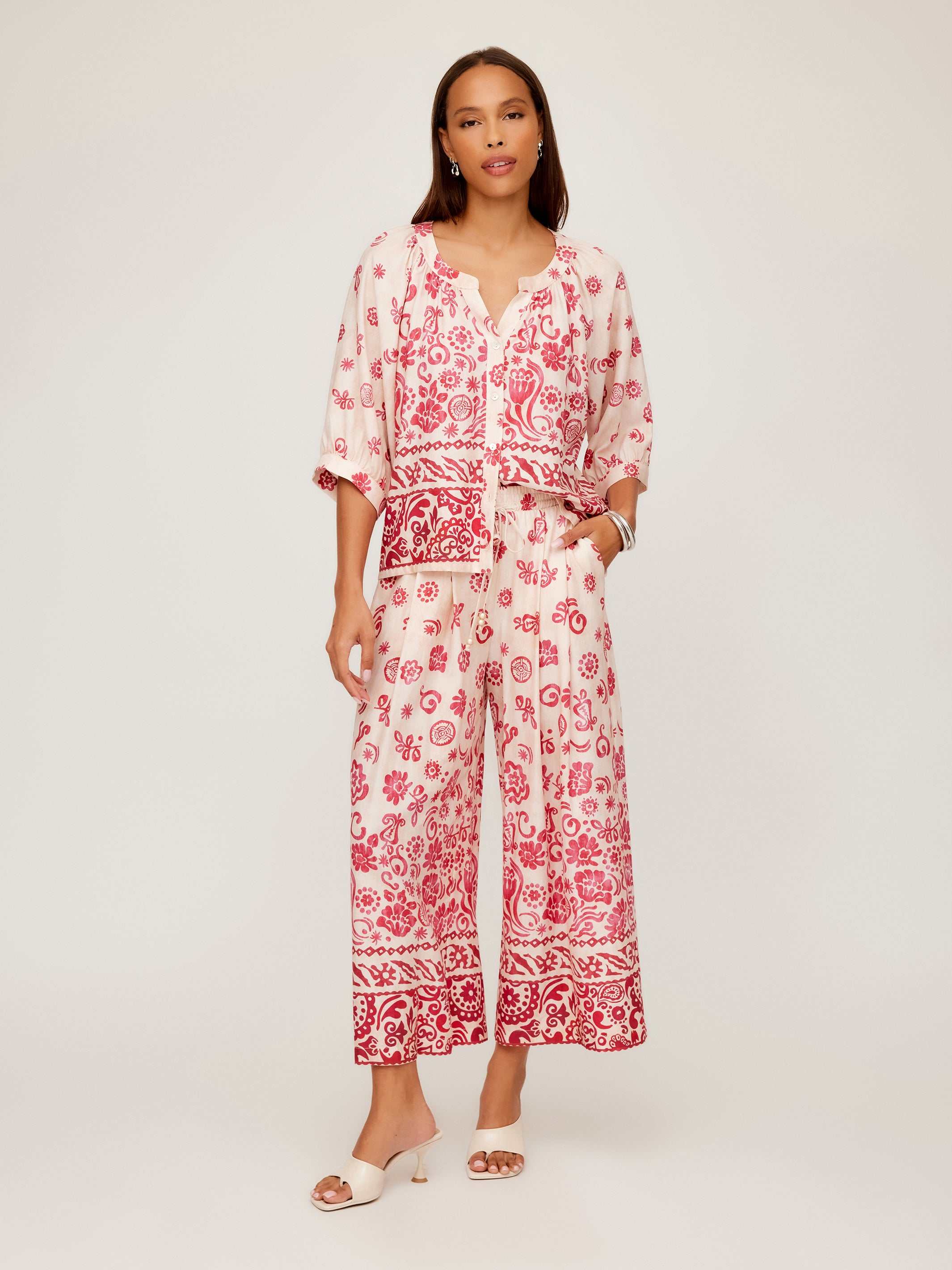 Woman wearing Etta Border Print Pants with watercolor border design and wide leg fit in red and white.