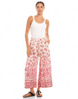 Woman wearing Etta Border Print Pants with wide leg, watercolor floral border design, elastic waistband, and side pockets.