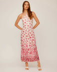 Woman wearing Jaylen Border Print Dress with pink floral watercolor border design, halter neckline, fitted silhouette, and side slits.