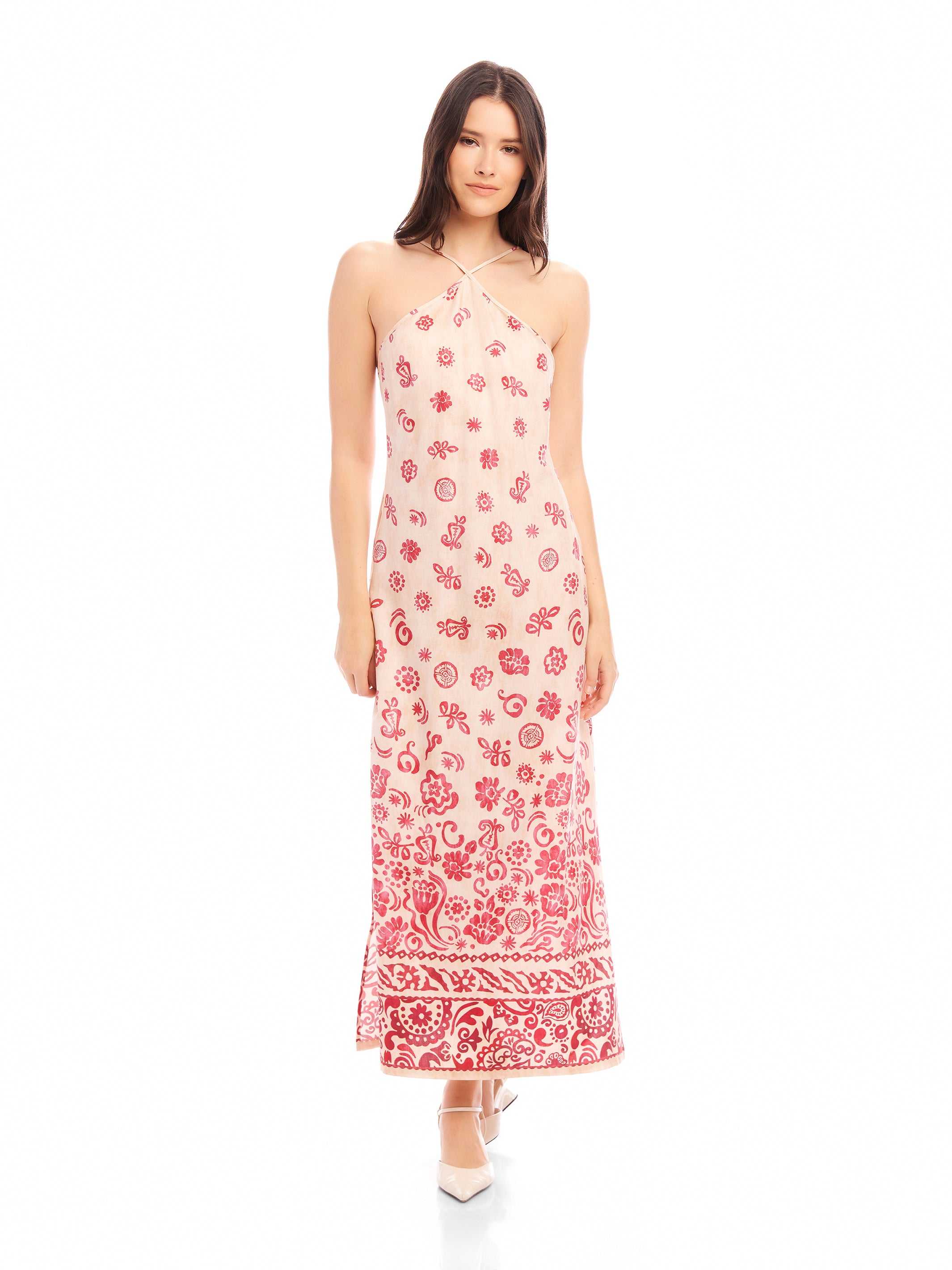 Model wearing a Jaylen Border Print Dress with a fitted silhouette, halter neckline, watercolor floral border design, and side slits.