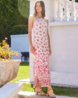 Woman wearing a fitted Jaylen Border Print Dress with halter neckline and side slits, standing outdoors near white pillars.