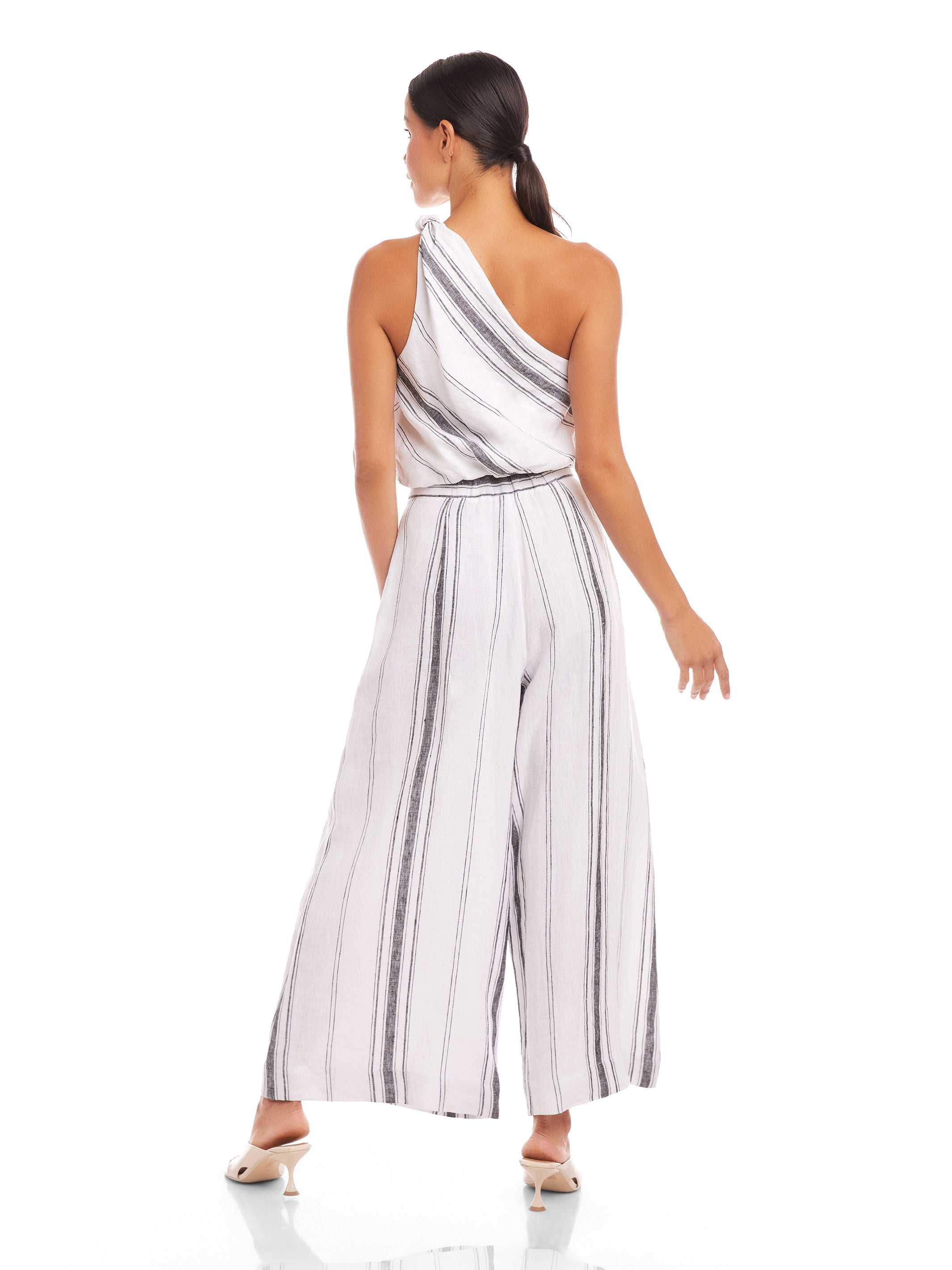 Back view of a woman wearing a striped Vanita One-Shoulder Top paired with wide-leg pants