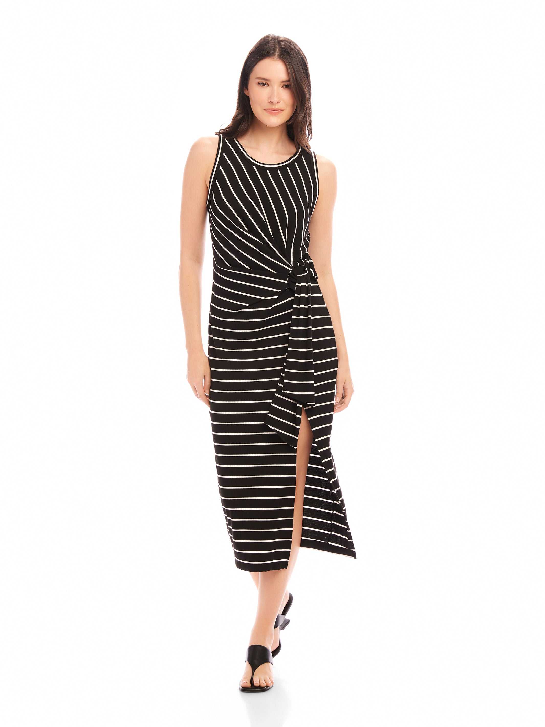 Woman wearing a black and white striped sleeveless Maddie Side-Knot Midi Dress with a side knot detail and front slit.