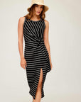 Woman wearing a black and white striped Maddie Side-Knot Midi Dress with sleeveless design, round neckline, front slit, and side knot detail
