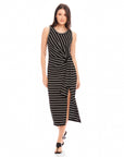 Woman wearing a black and white striped sleeveless Maddie Side-Knot Midi Dress with a side knot detail and front slit.