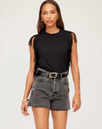 Woman wearing black Nora Fringe Tee with side and sleeve fringe details and high-waisted black denim shorts