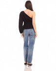 Woman wearing black Talia One-Shoulder Top with elasticized waist and asymmetrical long sleeve, paired with blue jeans.