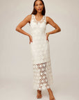 Woman wearing white sleeveless Kelsie Crochet Dress with floral pattern and scoop neckline