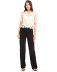Woman wearing Kamille Crochet Shirt with short sleeves and scalloped hem paired with black pants
