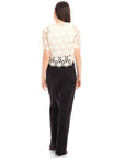 Back view of Kamille Crochet Shirt with floral pattern, short sleeves, scalloped hem, worn with black pants