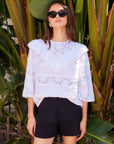 White Flora Eyelet Lace Top with embroidered floral eyelet design and ruffle trim, cotton fabric, elbow sleeves, and crew neck.