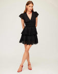 Woman wearing black Isla embroidered tiered dress with cap sleeves and V-neck paired with red heels and accessories