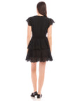 Back view of a woman wearing a black Isla Embroidered Tiered Dress with cap sleeves and tiered skirt
