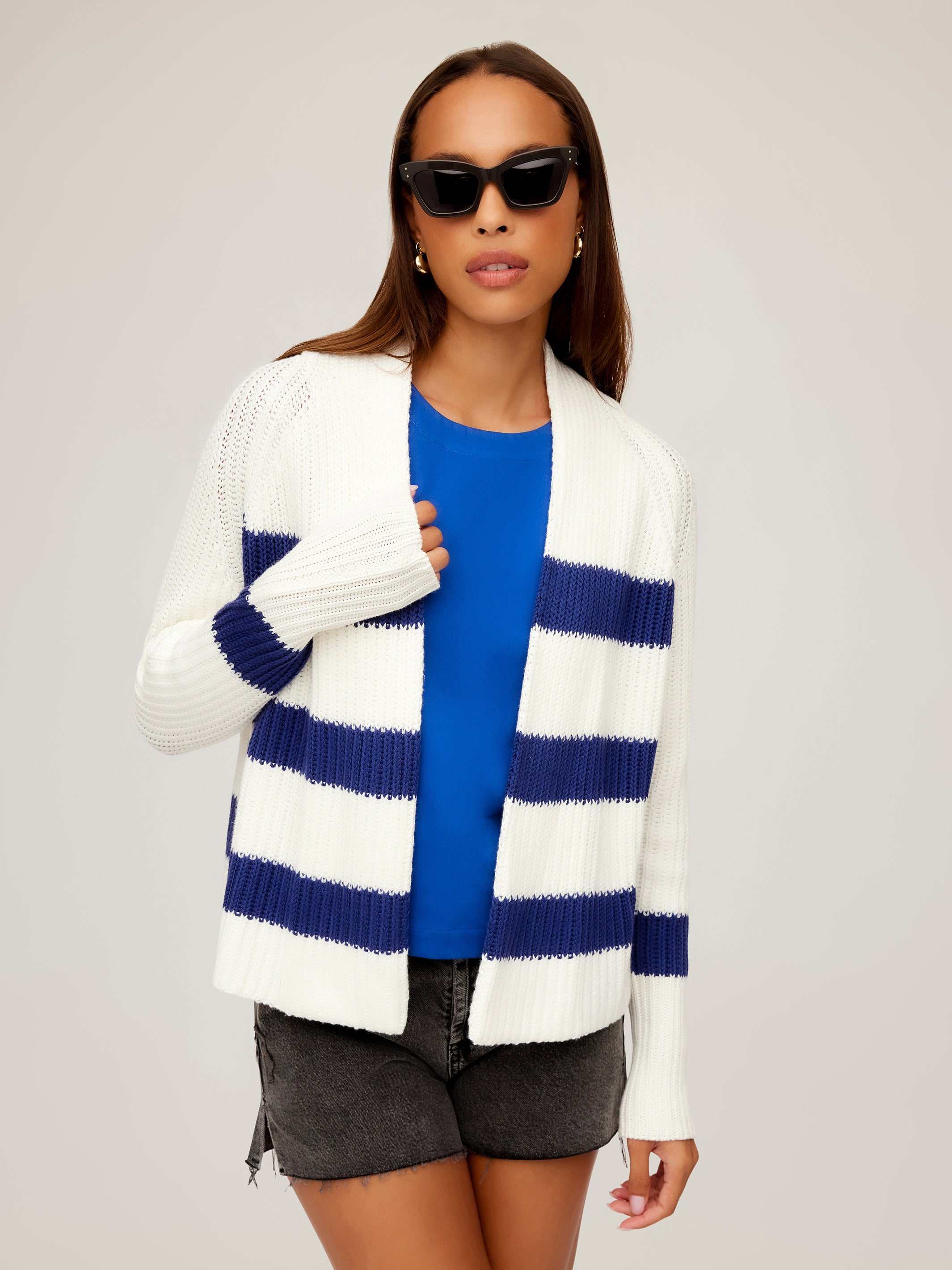 Woman wearing white and navy striped Cely Cropped Cardigan with blue top and black shorts