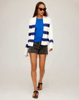 Woman wearing Cely Cropped Cardigan with white and navy stripes, blue top, black shorts, and sandals walking against plain background