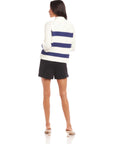 Woman wearing a white and blue striped Cely Cropped Cardigan with long raglan sleeves and black shorts, viewed from the back.