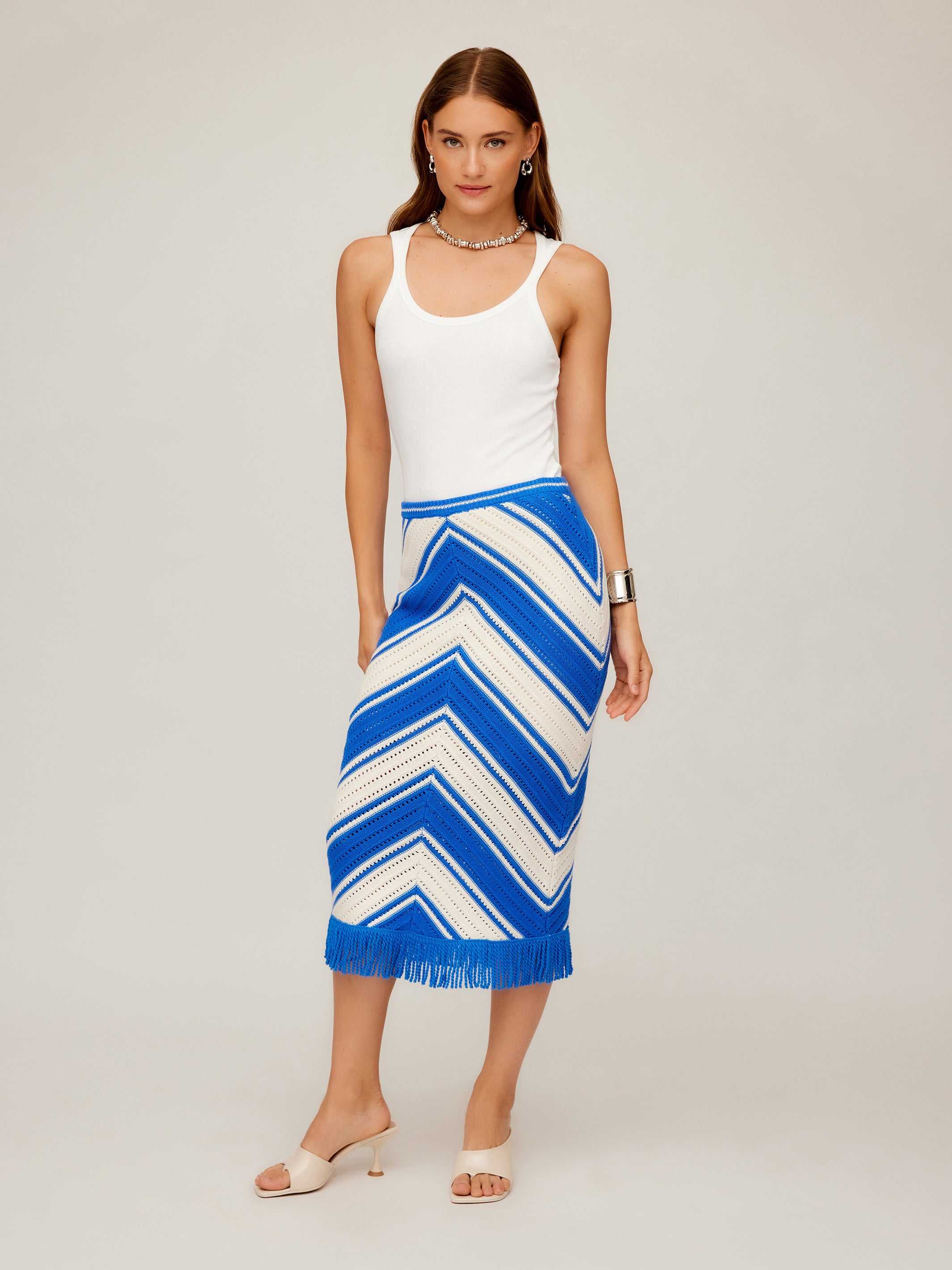 Woman wearing a fitted blue and white chevron pattern Amber Crochet Skirt with fringe hem and white tank top