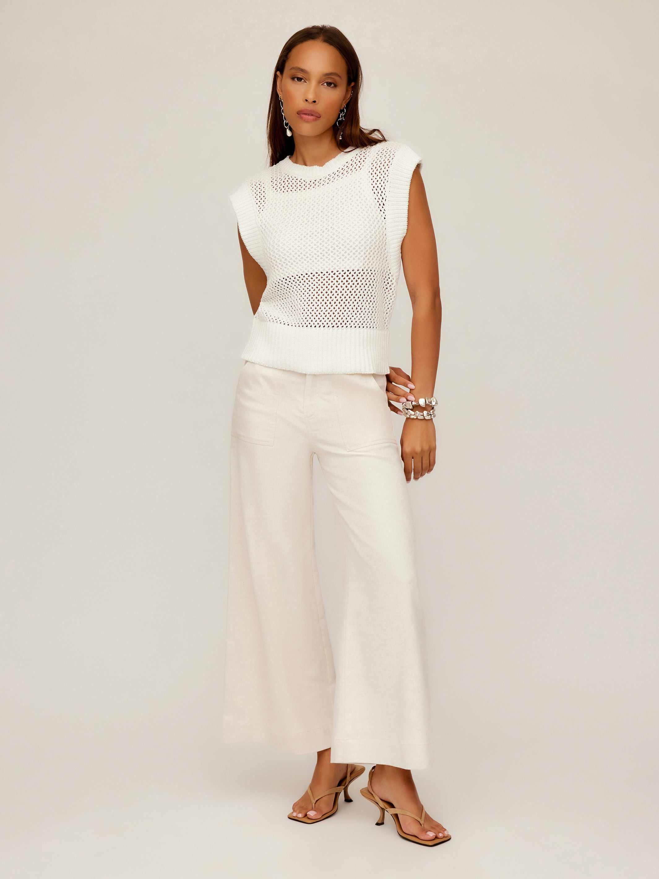 Woman wearing white Carly sleeveless crochet top with wide ribbed hem and cream wide-leg pants