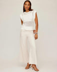 Woman wearing white Carly sleeveless crochet top with wide ribbed hem and cream wide-leg pants