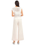 back view of woman wearing white Carly sleeveless crochet top with wide knit and crew neck paired with loose white pants