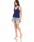 Woman wearing navy blue Nicole Sweater Tank with wide ribbed detail and white trim, paired with distressed denim shorts and beige heeled sandals.