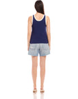 Woman wearing navy Nicole Sweater Tank with white ribbed trim and light denim shorts, shown from the back.