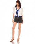 Women wearing Betsy Crochet Top with intricate eyelet stitching and scalloped hem, styled with black shorts and sandals