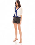 Woman wearing Betsy Crochet Top with blue scalloped edges and tie front closure paired with black shorts and heels