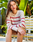 woman wearing Luca Crewneck Sweater with red stripes and ribbed cuffs sitting outdoors on yellow bench