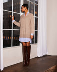 Woman wearing Carrie Mixed Media Dress with wheat sweater overlay and white with blue striped shirttail hem, paired with brown knee-high boots.