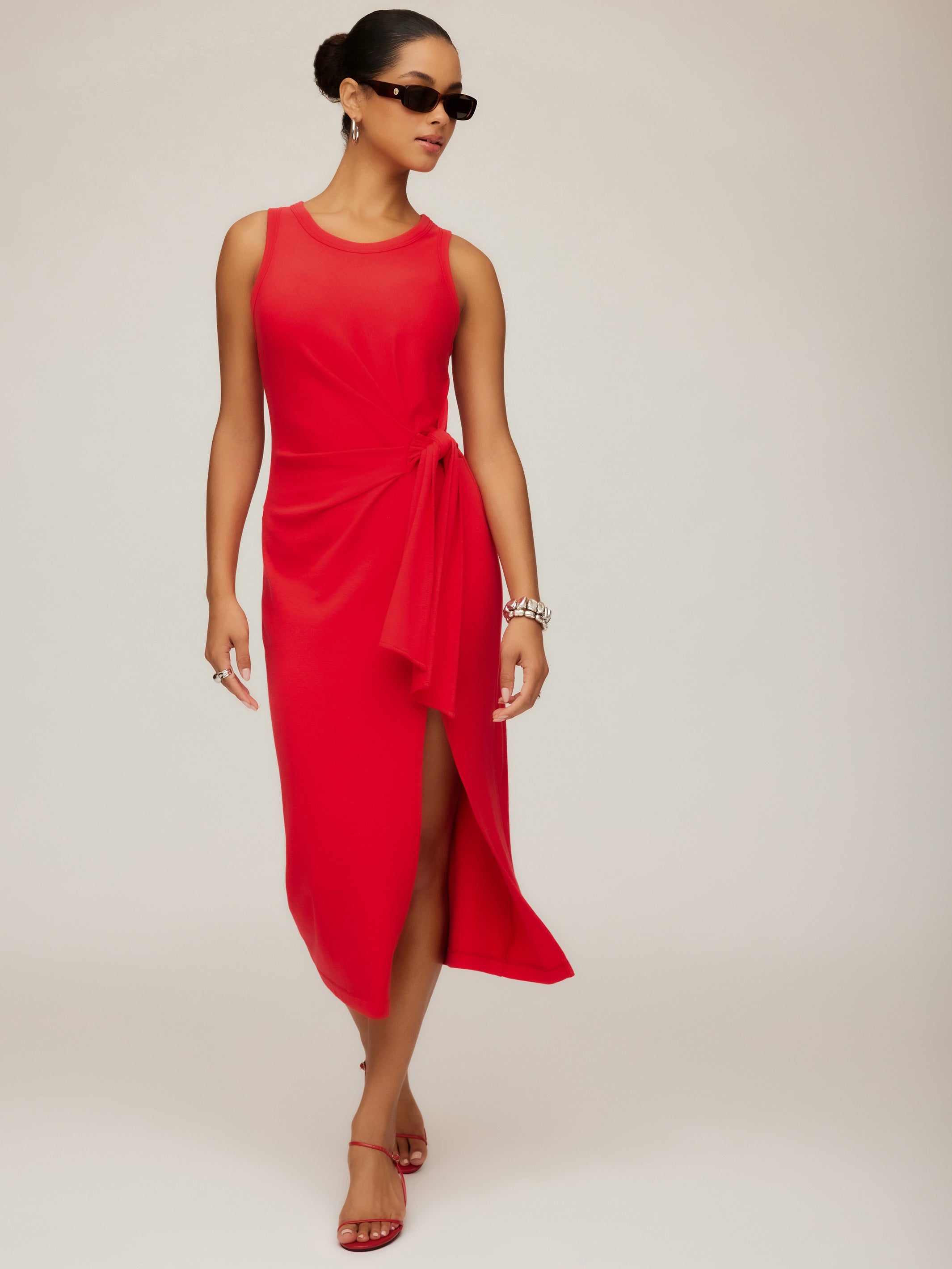 Woman wearing a red Maddie Side-Knot Midi Dress with sleeveless crew neck, side knot detail, and side slit.