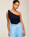 Woman wearing a black Harper One-Shoulder Tie-Top with tie detail, paired with light blue pants.
