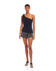 Woman wearing a navy Harper One-Shoulder Tie-Top with tie detail and asymmetrical silhouette paired with gray shorts and black sandals.