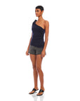 Woman wearing navy Harper One-Shoulder Tie-Top with tie detail and asymmetrical silhouette paired with black shorts and sandals