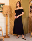 woman wearing black Ella Off-The-Shoulder midi dress with ruched sleeves and A-line silhouette standing indoors