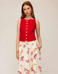 Woman wearing red Elis sleeveless button-up top with white functional buttons and patterned wide-leg pants.