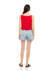 woman wearing red Elis sleeveless button-up top with boxy fit and light blue denim shorts back view