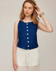 Woman wearing a navy Elis Sleeveless Button-Up Top with white buttons and white crochet shorts.