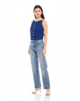 Woman wearing Elis sleeveless button-up top in blue linen with light blue jeans and heels