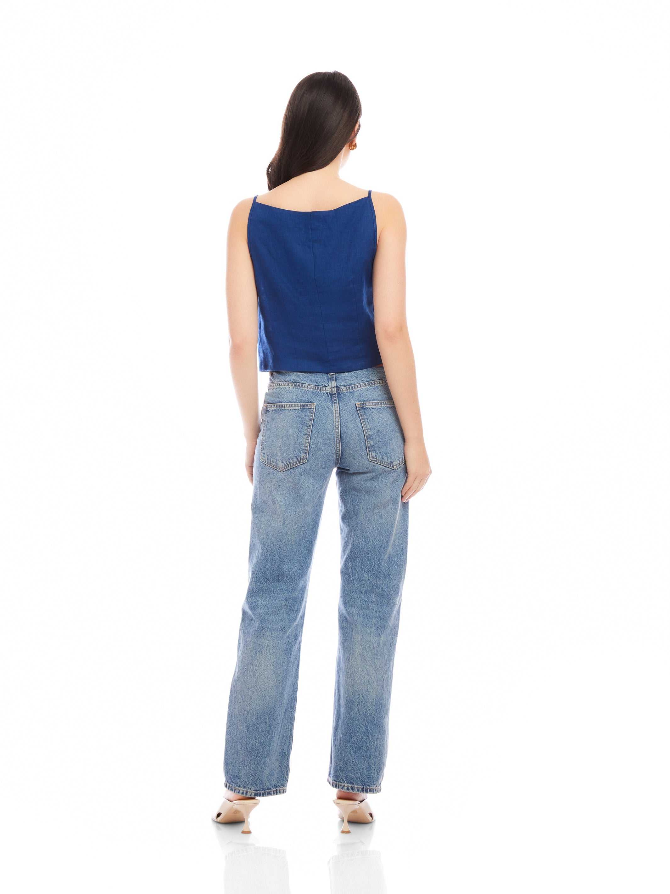 Woman wearing a navy Elis sleeveless button-up top with a boxy fit and light blue jeans, shown from the back