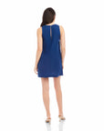 Woman wearing sleeveless navy blue Clarice Side-Button shift dress with back slit and keyhole button closure.