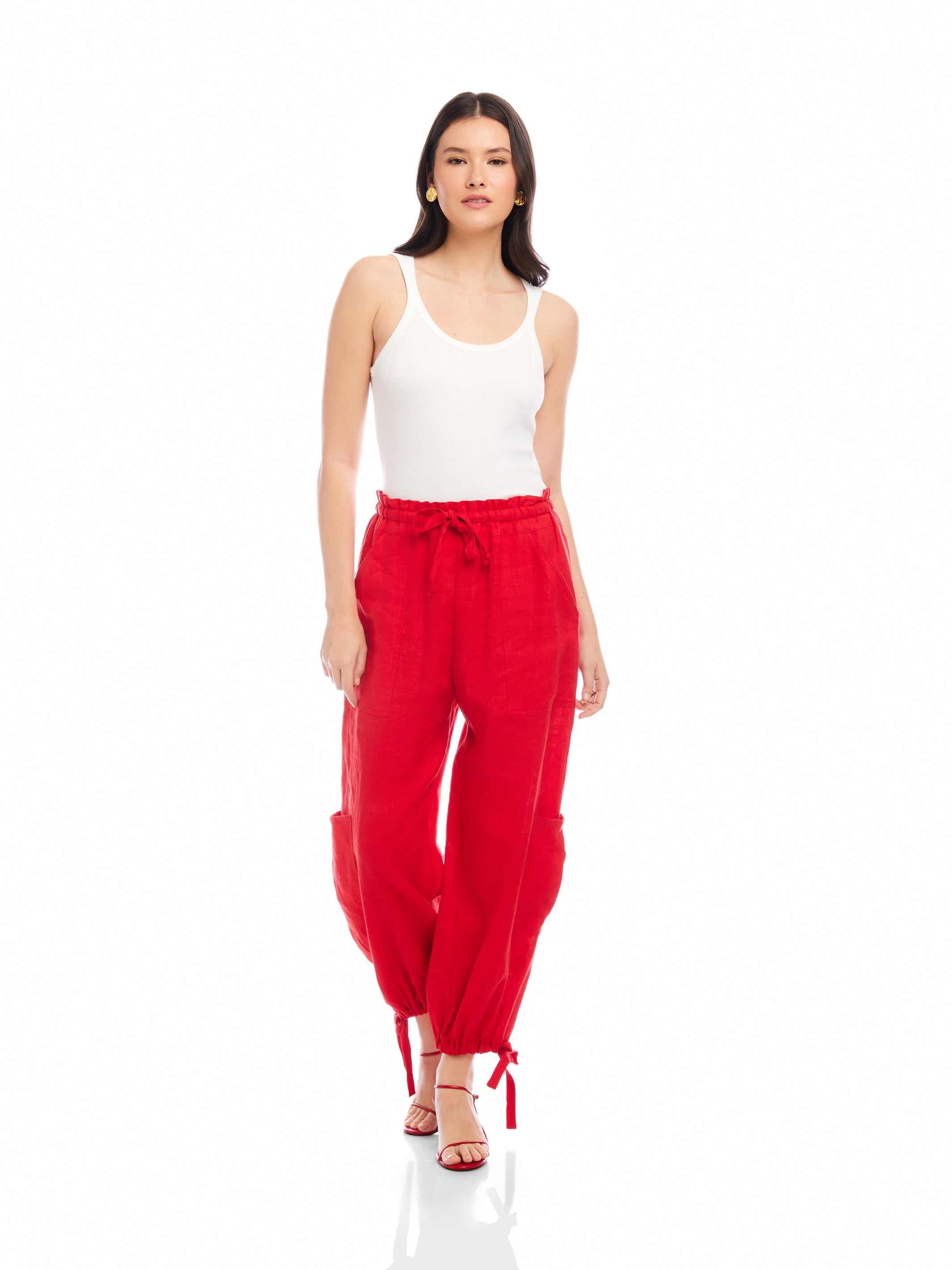 Woman wearing red Charo Cargo Pants with ankle drawstrings and front pockets paired with white tank top