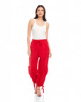 Woman wearing red Charo Cargo Pants with ankle drawstrings and front pockets paired with white tank top